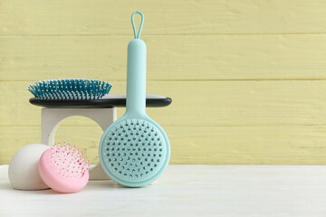 Different hair brushes on white wooden table