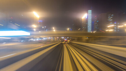 Front cabin POV view from modern driver-less metro train rush forward, along night Dubai, smooth timelapse.