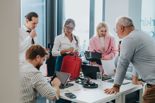 A diverse group of colleagues collaborates in a bright office, reviewing papers and devices. They share ideas, plan strategies, and discuss next steps, highlighting teamwork and business activity.