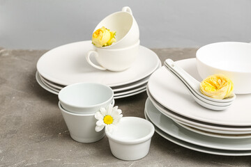 Simple tableware and flowers on table near grey wall