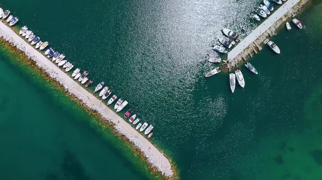 Straight down aerial view of the vibrant turquoise waters surrounding the boat piers of Nea Iraklitsa Marina, Kavala, Eastern Macedonia, Greece.
