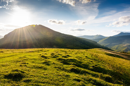 beautiful countryside at sunset. wonderful summertime landscape in mountains in evening light. scenic view of grassy field and rolling hills. rural scenery storytelling image under the rainbow
