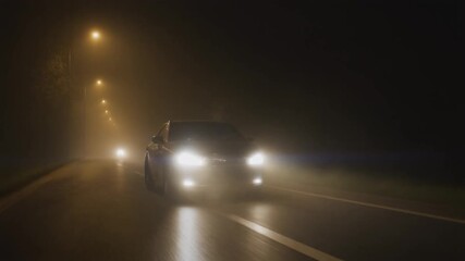 Car driving through dense fog at night on an illuminated highway. - Powered by Adobe