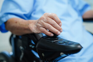 Asian elderly woman disability patient sitting on electric wheelchair in park, medical concept.