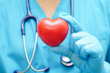 Asian woman doctor holding red heart for health in hospital.