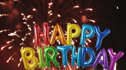 Happy Birthday colorful balloons with fireworks exploding in the night sky