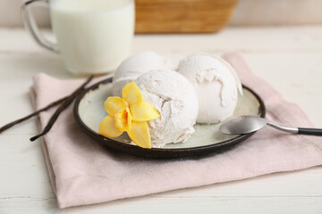 Plate of sweet vanilla ice-cream balls with flower and sticks on white wooden table