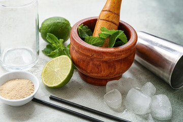 Naklejka premium Wooden mortar, pestle and ingredients for preparing mojito on grunge background, closeup