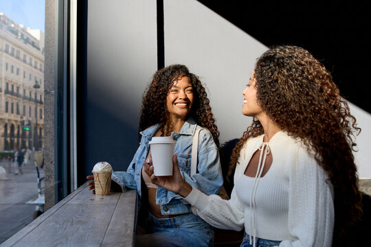 Two women friends enjoying coffee laughing in cafe
