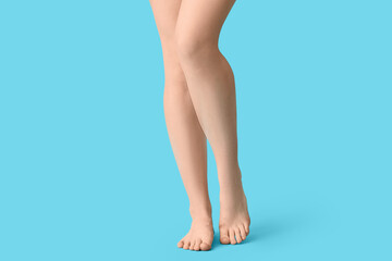 Legs of pretty young woman on blue background