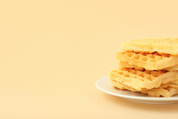 Delicious Belgian waffles in plate on yellow background