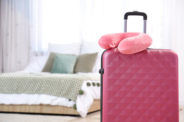 Neck pillow on suitcase in bedroom. Travel concept