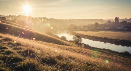 Misty English countryside valley at golden sunrise with river and distant village