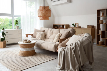 Armchair, sofa and wicker table with boxes in interior of living room