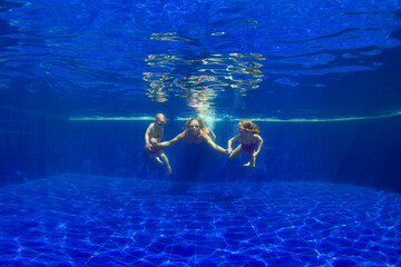 Happy family - mother, baby son, daughter in goggles swim, dive in pool with fun - jump deep down underwater. Healthy lifestyle, people water sport activity, swimming lessons on holidays with kids