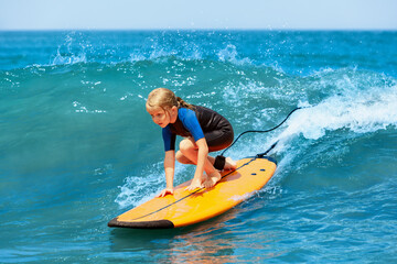Happy young surfer girl with surfboard have fun on beach, riding on small ocean waves. Summer adventures, active families, parents and kids lifestyle, sports activities on school holiday with kids