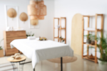 Blurred view of light spa salon with massage couch, fans and shelf units