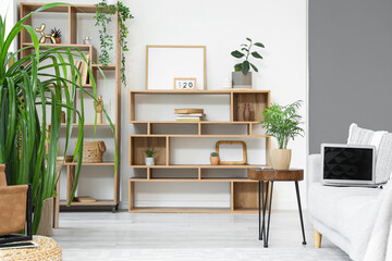Interior of living room with shelf units, plants and laptop on sofa