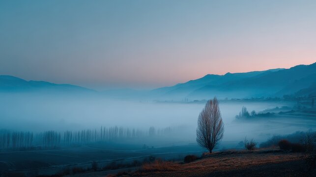 Scene of a foggy valley featuring a solitary tree at twilight - Powered by Adobe