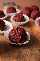 Wooden board with delicious chocolate truffles in paper cups, closeup