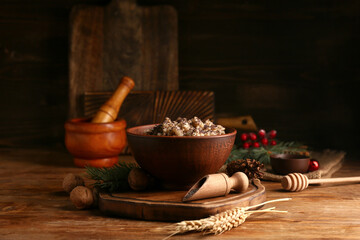 Bowl of traditional Ukrainian Kutya dish with walnuts and fir branch on wooden background