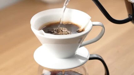Close-up image captures coffee brewing process with a dripper, filter, and hot water being poured