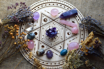 Rose quartz and natural amethyst crystals, along with dried lavender herbs, are arranged on a wooden altar for divination. Fortune-telling, witchcraft, and spiritual esoteric practice.