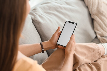 Young woman using blank mobile phone on sofa at home, closeup