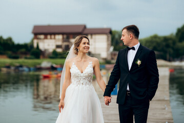 young couple, the bride and groom, walking along a pier