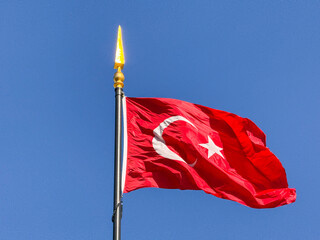 Turkish national flag waving on a tall pole against clear blue sky