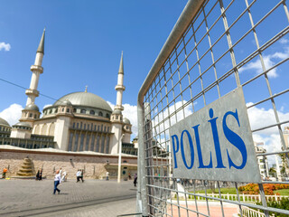 Police barricade on Taksim Square with mosque in the background symbolizing public safety and political unrest