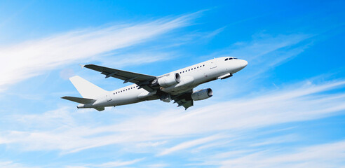 White passenger airplane in the flight, travel background with flying airplane over the clouds