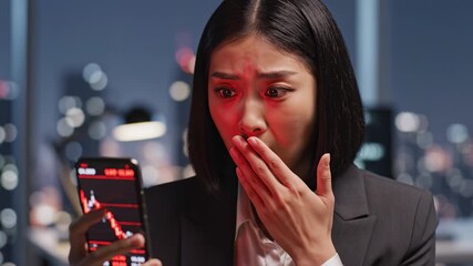 Shocked businesswoman in office at night looking at smartphone with falling stock market graph showing financial loss, investment concern, and stress about market decline and office environment - Powered by Adobe