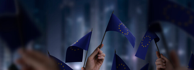 European Union flags in their hands on a blurred urban background