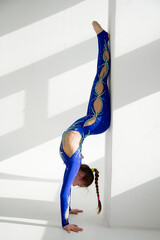 young woman in blue acrobatic suit doing yoga exercise. Handstand. Sport  conception