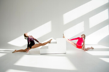 two young beautiful gymnast girls posing in white studio