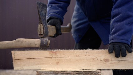 Carpenter using axe and hammer for woodwork