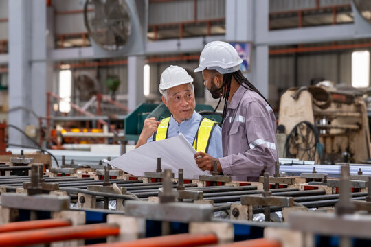 Industrial Engineer in Hard Hats.Work at the Heavy Industry Metal Sheet Manufacturing Factory. Factory worker indoors in metal sheet factory. Man working in an industrial factory. - Powered by Adobe