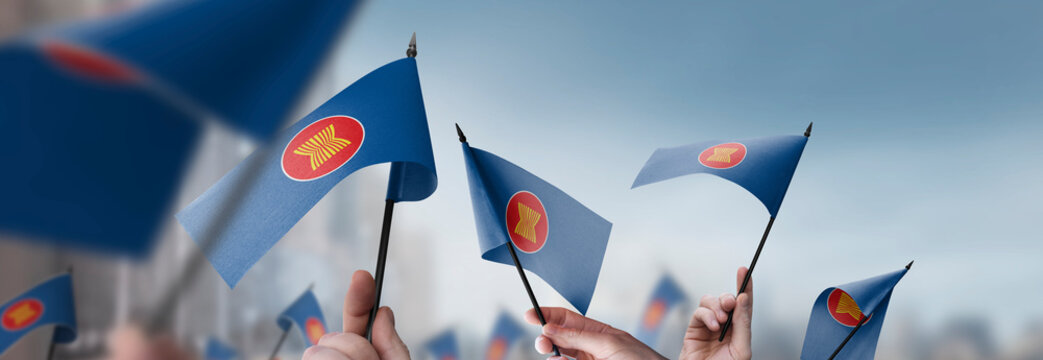 ASEAN flags in their hands on a blurred urban background