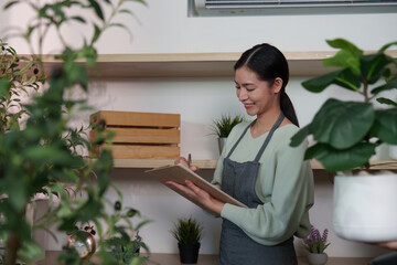 Sustainable Lifestyle. Woman enjoying plant care while taking notes in a shop setting.