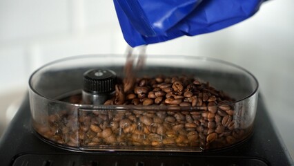 Pouring fresh roasted coffee beans into an electric grinder