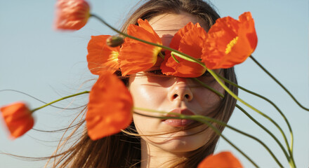Woman with face covered by orange poppy flowers. Natural beauty and spring season concept. Close-up artistic portrait.