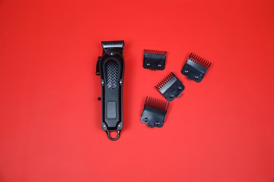 Compact electric trimmer with multiple detachable combs arranged around it on a red surface, ideal for grooming, beard shaping, and precise hair cutting.