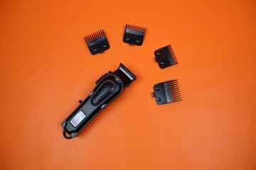 Compact electric trimmer with multiple detachable combs arranged around it on a orange surface, ideal for grooming, beard shaping, and precise hair cutting.