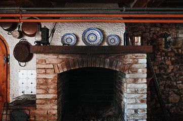 An old fireplace inside a cozy home with vintage dishes placed on top. The scene radiates warmth, nostalgia, and a rustic European charm with soft natural lighting.