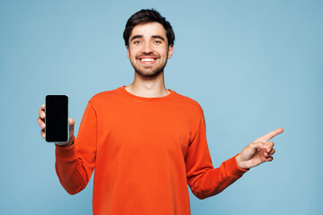 Young man wear orange sweatshirt casual clothes hold in hand use mobile cell phone with blank...