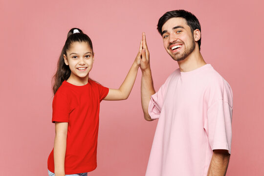 Young parent man with child girl wear red casual clothes. Daddy little kid meet together greet give high five clapping hand folded isolated on plain pink background Father's Day Love family concept