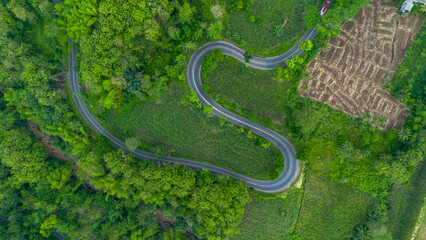 Aerial view of winding road in Malang, East Java, Indonesia surrounded by tropical green hills