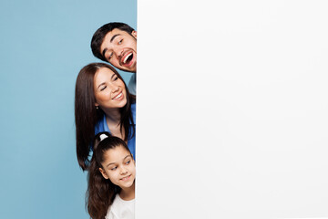 Young happy parents mom dad with child kid daughter girl wear casual clothes hold blank sign board poster for promotional content place for text isolated on plain blue background Family day concept.