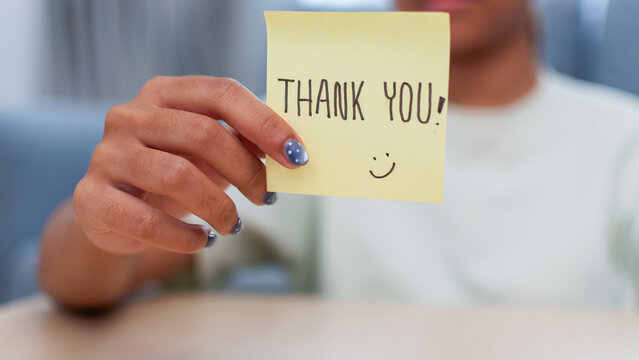 Grateful gesture person holding thank you note indoor setting emotional connection close-up view